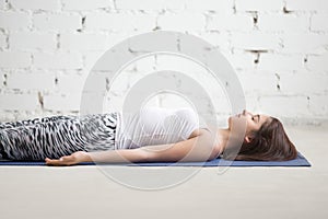 Young attractive woman in Savasana pose, white studio, closeup