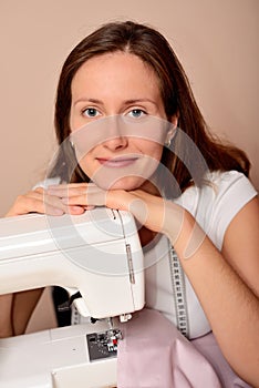 Young attractive woman sewing on machine