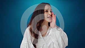 Young attractive woman shouting against blue background