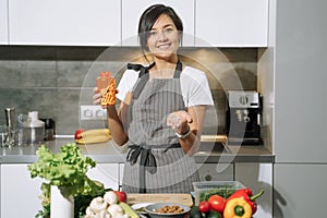 Young attractive woman showing nutritional supplements or vitamins in the kitchen. Balanced nutrition, health and diet concept