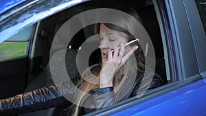 Young Attractive Woman Sits In A Parked Car And Swears By Phone