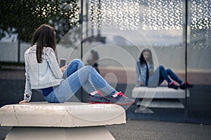 Young and attractive woman is sitting on the bench in industrial park.