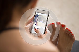 Young attractive woman sitting and checking pictures on her smar