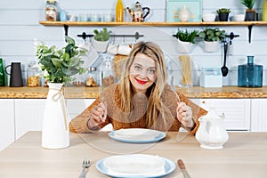 Young attractive woman sitting at table in kitchen