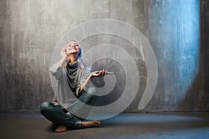 Young and attractive woman with smartphone and large headphones, sitting on the floor. Music in the mobile app.