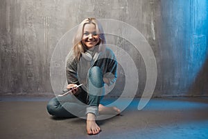 Young and attractive woman with smartphone and large headphones, sitting on the floor. Music in the mobile app.