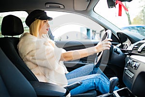 Young attractive woman smiling and looking straight while driving a car