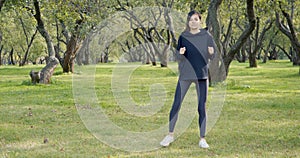 Young attractive woman in sportswear doing squat exercises in the park outdoors. Healthy lifestyle concept