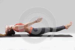 Young attractive woman stretching in Matsyasana pose, grey studi