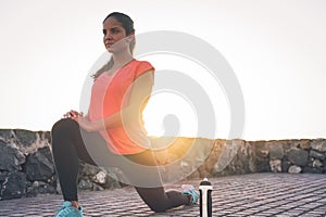 Young attractive woman stretching next the beach during a magnificent sunset - Sporty health girl workout outdoor photo