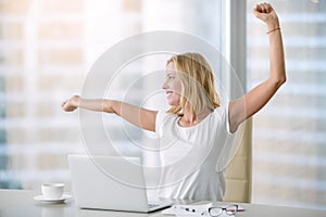 Young attractive woman stretching at office desk