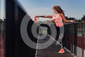 Young attractive woman stretching outdoor in an urban setting on a sunny day