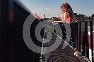 Young attractive woman stretching outdoor in an urban setting on a sunny day