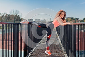 Young attractive woman stretching outdoor in an urban setting on a sunny day