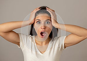 Young attractive woman with a surprised and shocked face, eyes and mouth wide open.