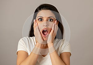 Young attractive woman with a surprised and shocked face, eyes and mouth wide open.