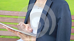 Young attractive woman with tablet computer sitting in garden