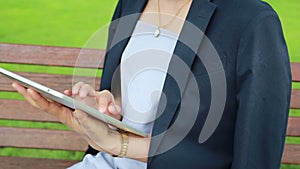 Young attractive woman with tablet computer sitting in garden