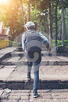 Young attractive woman tourist with backpack coming to ancient p