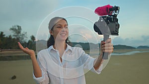 Young attractive woman travel blogger or vlogger recording video movie and looking at camera and talking on video