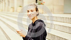 Young attractive woman using phone in city. Sending a message.