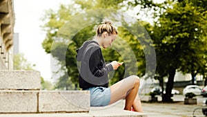 Young attractive woman using phone in city. Sitting and smileing.