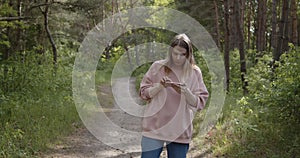 Young attractive woman using smartphone to navigate in a summer forest