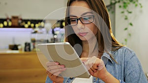 Young attractive woman using tablet touch screen and in modern cafe