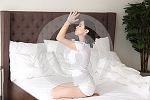 Young attractive woman in vajrasana pose on the hotel bed