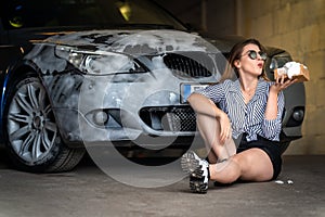 A young attractive woman washes a car with a sponge and foam