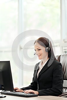 A young attractive woman wearing a black jacket in a black jacket is sitting at her desk in a executive chair. Holds a