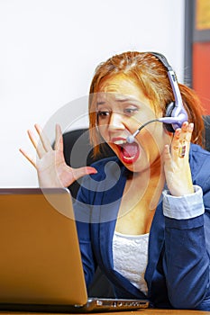 Young attractive woman wearing office clothes and headset sitting by desk looking at computer screen, upset body