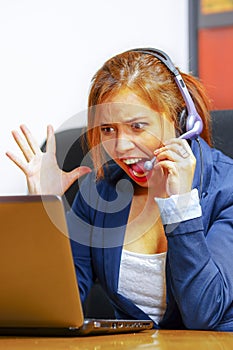 Young attractive woman wearing office clothes and headset sitting by desk looking at computer screen, upset body