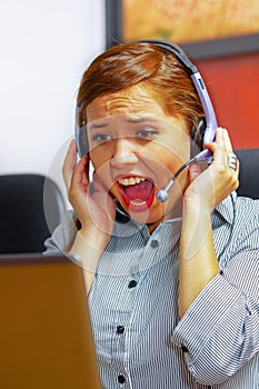Young attractive woman wearing office clothes and headset sitting by desk looking at computer screen, upset body
