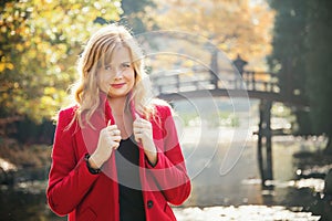 Young attractive woman wearing in red coat in autumn city park