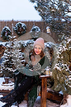 Young attractive woman in winter clothes sitting in a chair and relaxing outside