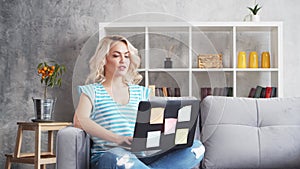 Young and attractive woman works at home using laptop computer. Freelancer or student on the couch.