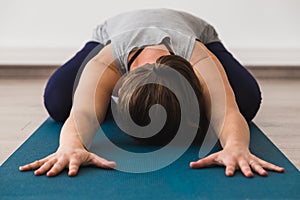 Young attractive woman on yoga mat doing child`s pose