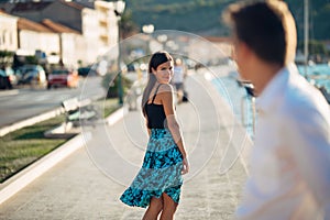 Young attractive woman flirting with a man on the street.Flirty smiling woman looking back on a handsome man.Female attraction photo