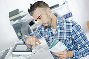 Young attractive worker man working using printmaking device