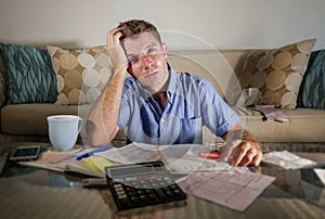 Young attractive worried and stressed man at home calculating mo