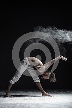 Young attractive yogi man practicing yoga, standing in Parivrtta Parsvatanasana exercise, working out