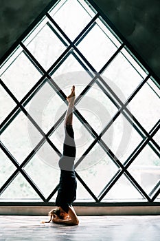 Young attractive yogi woman practicing yoga standing in supported headstand pose