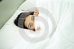 Young attrative Asian woman on white pillow and bed sheet in bedroom relaxing on holiday