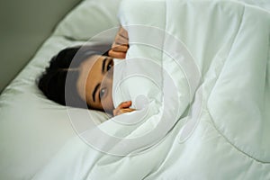 Young attrative Asian woman on white pillow and bed sheet in bedroom relaxing on holiday