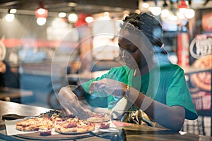 Young authentic black woman sitting with phone in city coffee shop at night