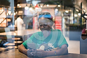 Young authentic black woman sitting with phone in city coffee shop at night