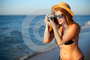 Young authentic woman with vintage retro film camera enjoying tropical beach on summer vacation. Female travel