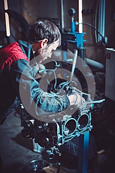 The young auto mechanic dismantles the opposing engine.