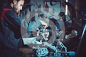 The young auto mechanic dismantles the opposing engine.